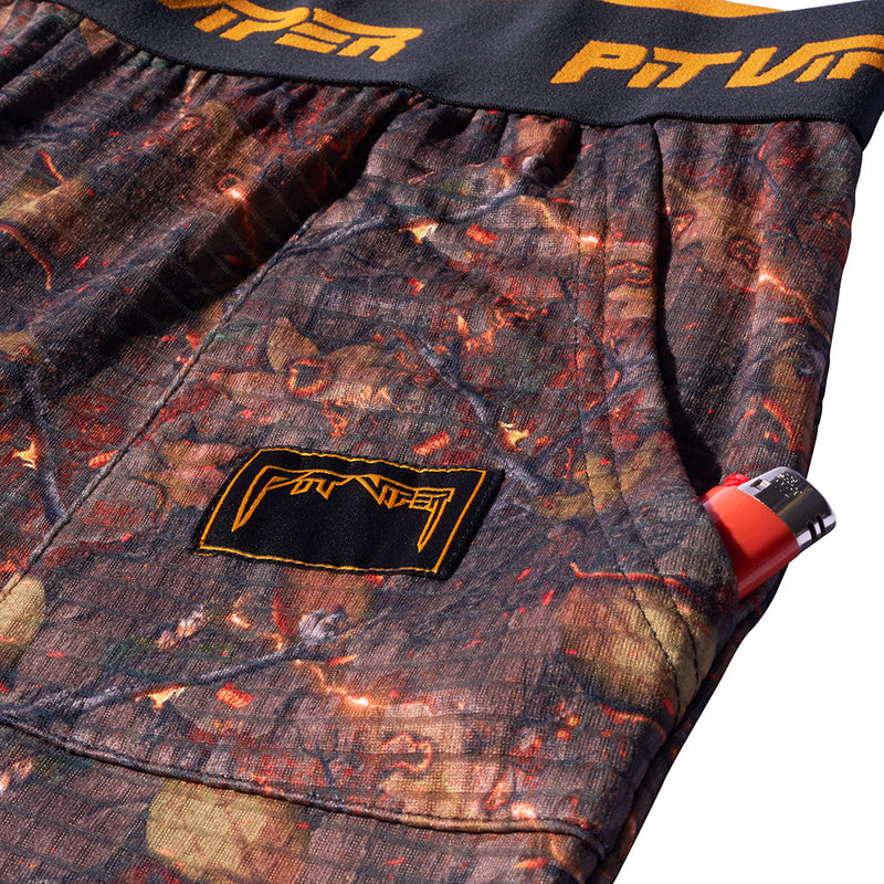 | its_a_pocket.JPG | Close-up of camouflage-patterned shorts with a black waistband featuring orange lettering and a black patch with orange branding on the left leg.