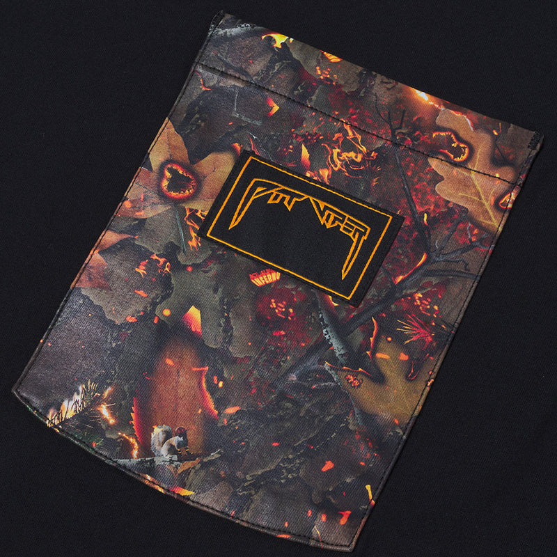 | detail_shot.JPG | A fiery camouflage pattern shirt pocket in black, red, and orange, featuring a black rectangular patch with a yellow stylized logo on the front, set against a solid black background.