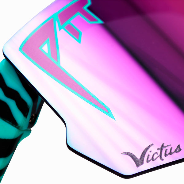 | im_ready_for_my_closeup.JPG | Close-up of a Victus sunglasses lens showing a pink and purple iridescent finish with a teal logo outline and a black-and-teal striped temple arm.