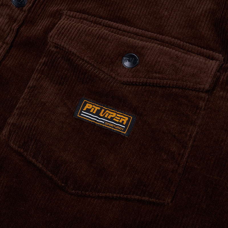 | pocket.JPG | Close-up of a dark brown corduroy jacket with a chest pocket, featuring a black snap button and a rectangular Pit Viper embroidered patch.