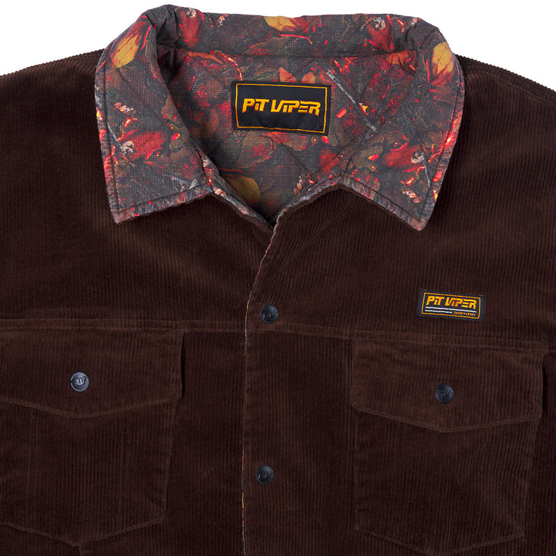 | detail_shot.JPG | A close-up of a dark brown corduroy button-up shirt jacket by Pit Viper, featuring a patterned inner collar with red, orange, and black tones, and a small Pit Viper logo patch on the chest pocket.