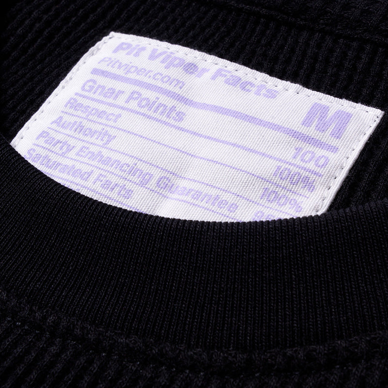 | healthJPG | Close-up of a white rectangular fabric label sewn onto the inside collar of a black ribbed knit garment. The label has purple text reading 'Pit Viper Facts', 'pitviper.com'