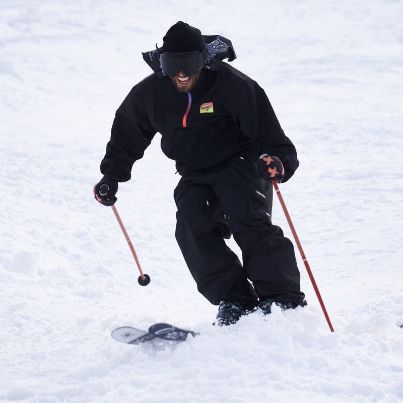 / Smoke | weeeee.JPG | A person skiing through deep snow, wearing a black ski jacket, black ski pants, black gloves, a black beanie, and black goggles, holding red ski poles.