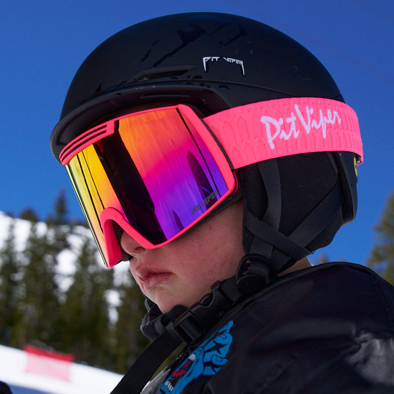 | photo_of_kid.JPG | Close-up of a skier wearing a black helmet and bright pink goggles with a reflective rainbow lens and a pink strap branded Pix Vision.