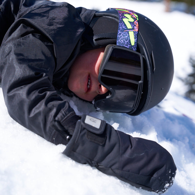 Smoke / Small | wipeout.JPG | A person lying in the snow wearing a black ski helmet with a colorful patterned strap, black ski goggles, a black snow jacket, and a black snow glove.