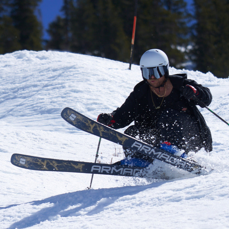 | photo_of_the_chuck.JPG | A skier in a black jacket, white helmet, and goggles carving through fresh snow, with Armani Armani skis visible and pine trees in the background.