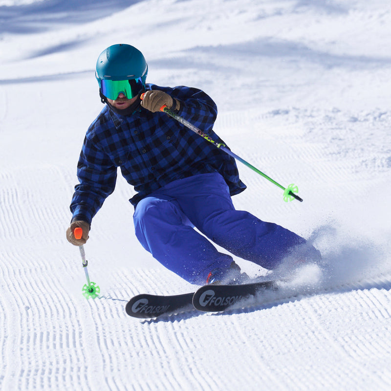 | corduroy_chuck.JPG | A skier carving through fresh powder snow, wearing a blue and black plaid shirt, bright blue pants, a teal helmet, mirrored green goggles, and using ski poles with bright green tips. 