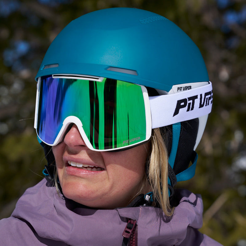 | barbara.JPG | A close-up of a person wearing a teal ski helmet and large mirrored ski goggles with a white strap branded 'PIT VIPER'. The background shows blurred outdoor trees in winter light.