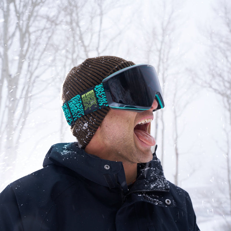 HDPV Smoke | it_is_a_nick.JPG | A man wearing a brown knit beanie, a dark navy winter jacket, and teal and black ski goggles with snow in the background.