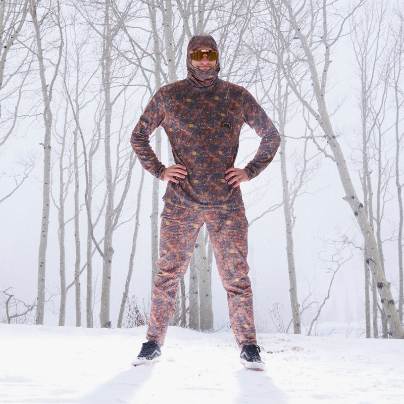| yes_nick.JPG | A man wearing a full-body camouflage winter tracksuit with a hood, face covering, and orange-tinted sunglasses stands in a snowy forest with bare trees.