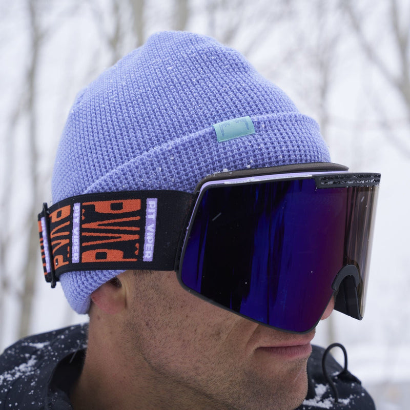 / Smoke | hello_nick.JPG | A close-up of a person outdoors in the snow wearing a light purple knit beanie and ski goggles with a black strap featuring orange and white 'PIT VIPER' branding.
