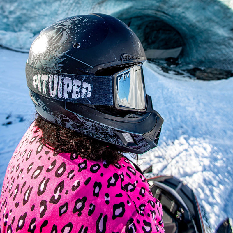Silver | braaaap2.JPG | A person in a snowy outdoor setting wearing a black full-face helmet with a reflective visor and a bright pink leopard-print jacket, with an ice cave in the background.