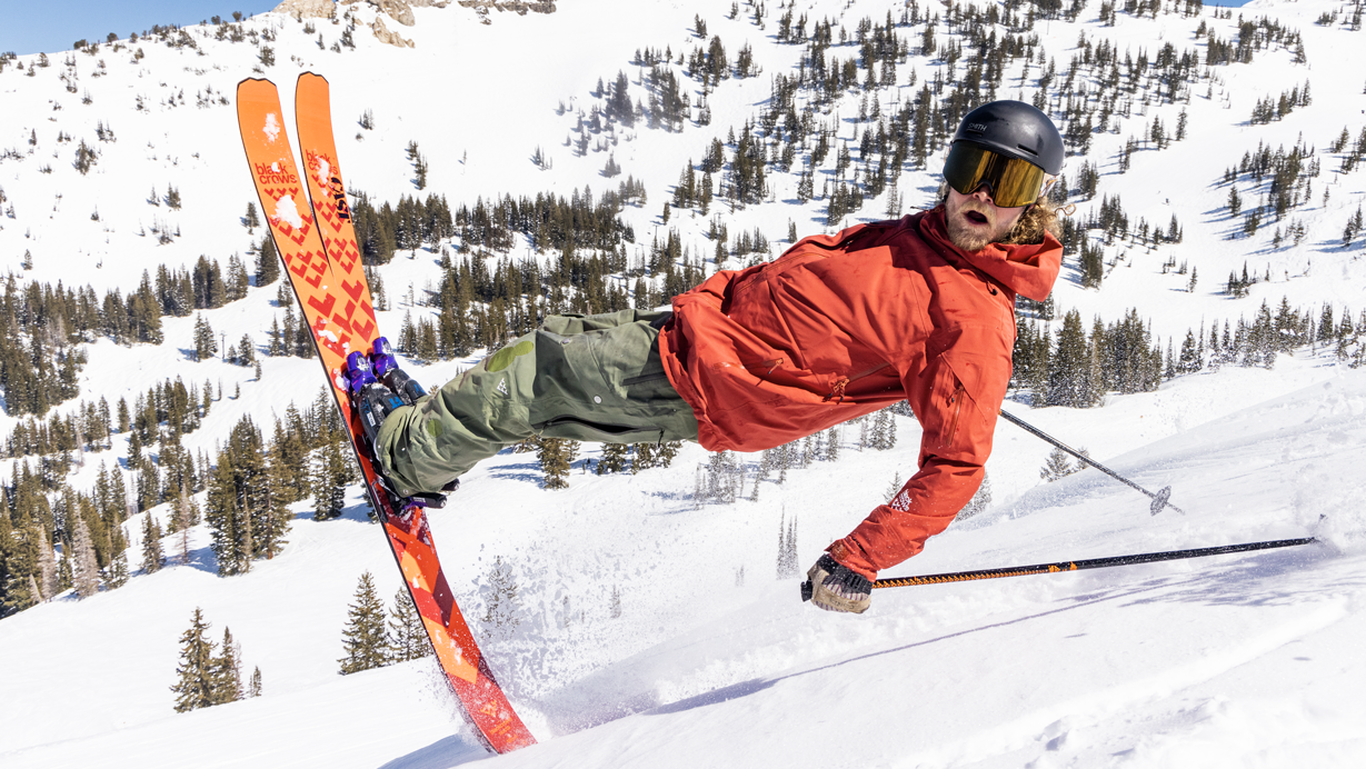 Person skiing in a snowy mountain landscape with a clear blue sky