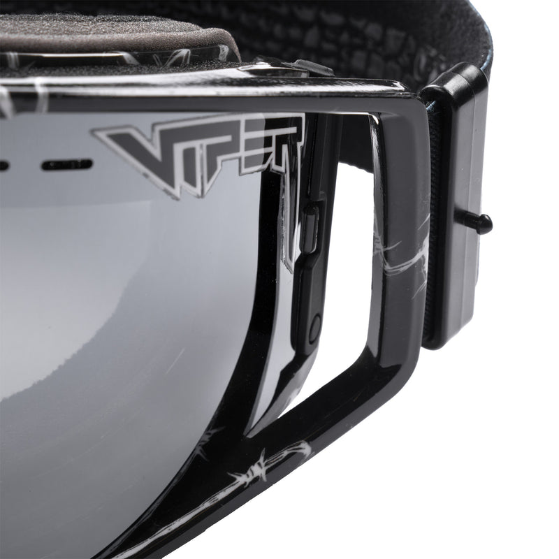 Silver | even_more_closeup.JPG | Close-up of black Pit Viper goggle hardware and strap with a reflective gray lens, shown on a white background.