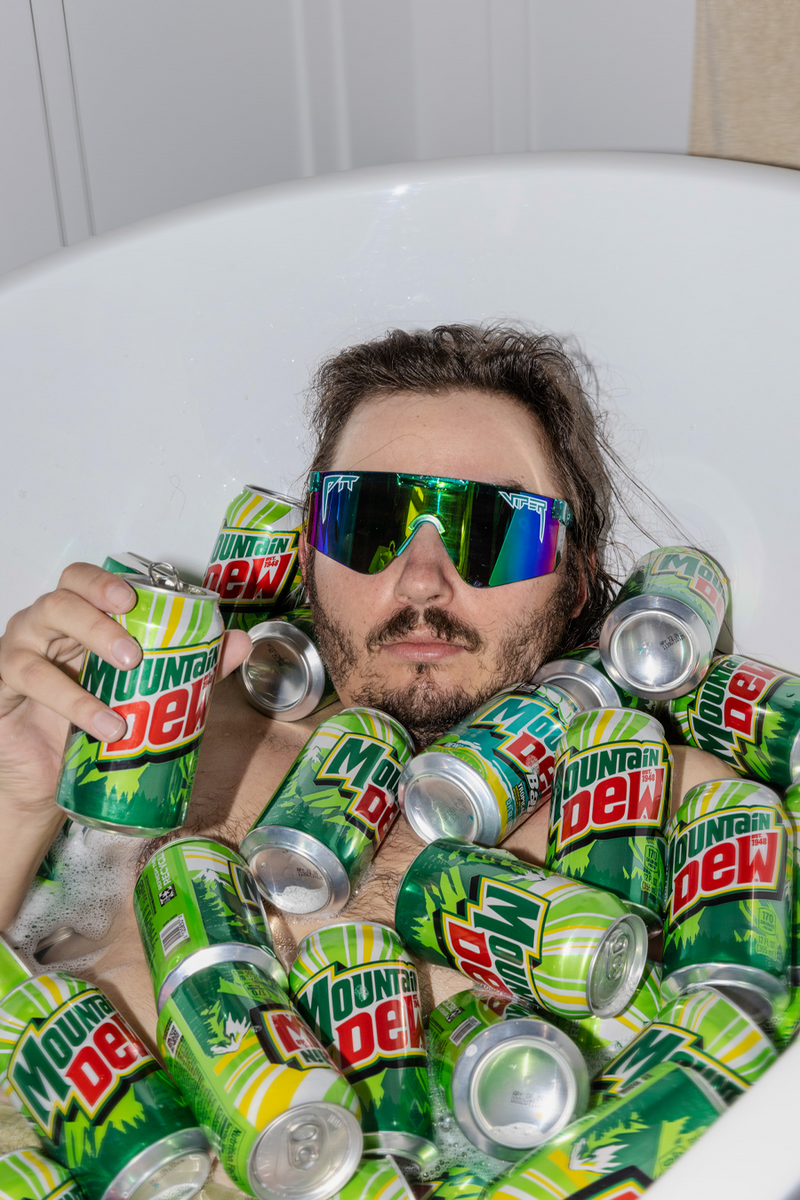 Person surrounded by Mountain Dew cans in a bathtub